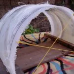 Fiberglass tunnel fin taking shape over a wooden jig on a resin-swirl board