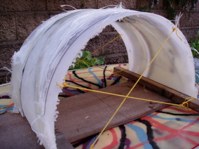 Fiberglass tunnel fin taking shape over a wooden jig on a resin-swirl board