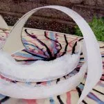 Raw fiberglass hoop fin arcing over a resin-swirl board during construction