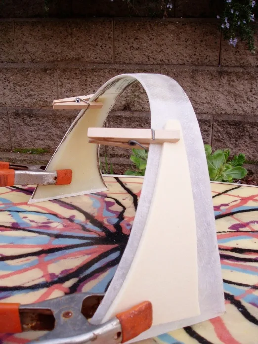 Clothespins and clamps holding a hoop fin's foam core during lamination