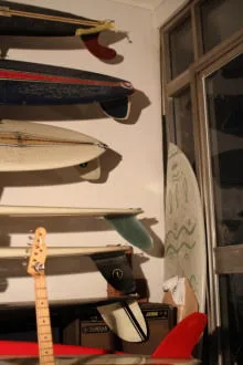 Go Yukioka's surfboard collection racked up a wall beside a guitar