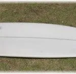 White fish-tailed board on grass fitted with a black hoop fin