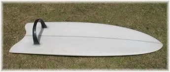 White fish-tailed board on grass fitted with a black hoop fin