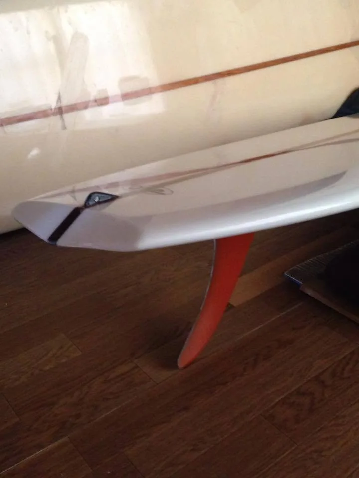 Long raked orange flex single fin under a white board indoors