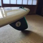 Cream longboard on a tatami mat with a dark green glassed-on single fin