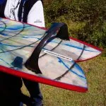 Resin-swirl fish with red rails and a black hoop center fin, carried by its maker