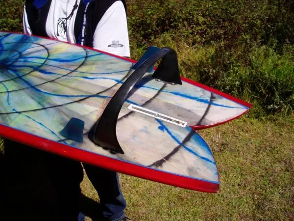 Resin-swirl fish with red rails and a black hoop center fin, carried by its maker